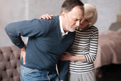 Too strong. Portrait of aged man standing with terrible ache in back while his wife supporting him.