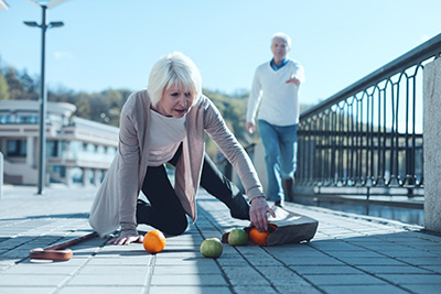 Scared woman dropping groceries while falling to ground