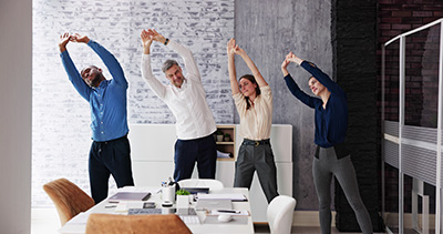 Exercise In Corporate Business Office. Diverse Team Standing Near Desk