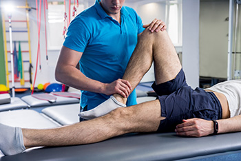 Rehabilitation therapy. Physiotherapist working with young male patient in the rehabilitation center. Treatment pain in spine